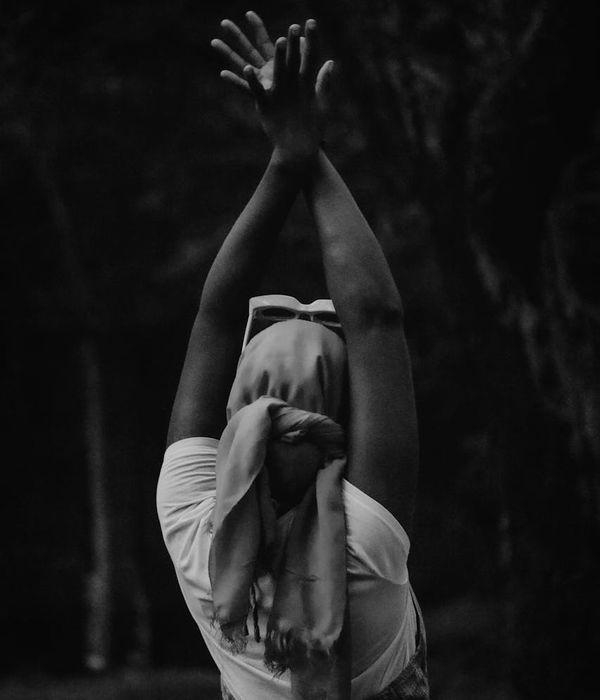 Woman in a calm yoga pose against a dark slate background.